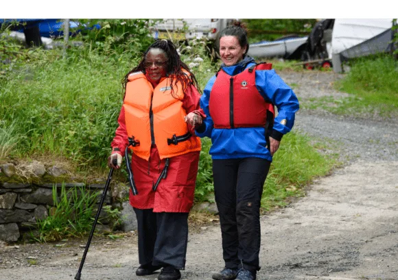 Two women supporting each other during an outdoor activity